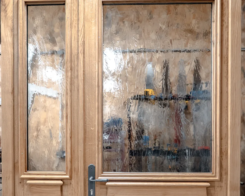Porte à deux vantaux en chêne, panneaux moulurés et vitrages, montée à l’atelier