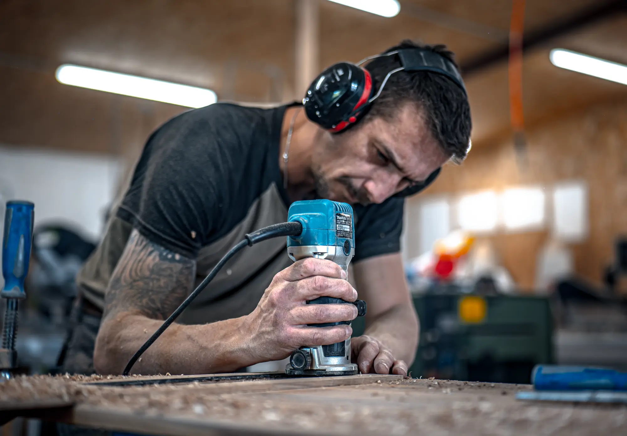 Menuisier travaillant une pièce de bois à la défonceuse, dans l’atelier
