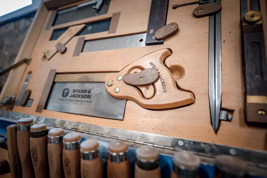 Scies, ciseaux à bois et outils à main rangés au mur de l’atelier