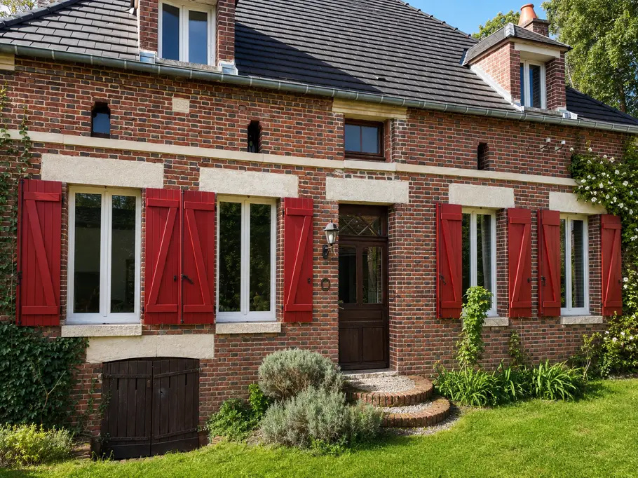 Maison de brique aux volets bois peints en rouge
